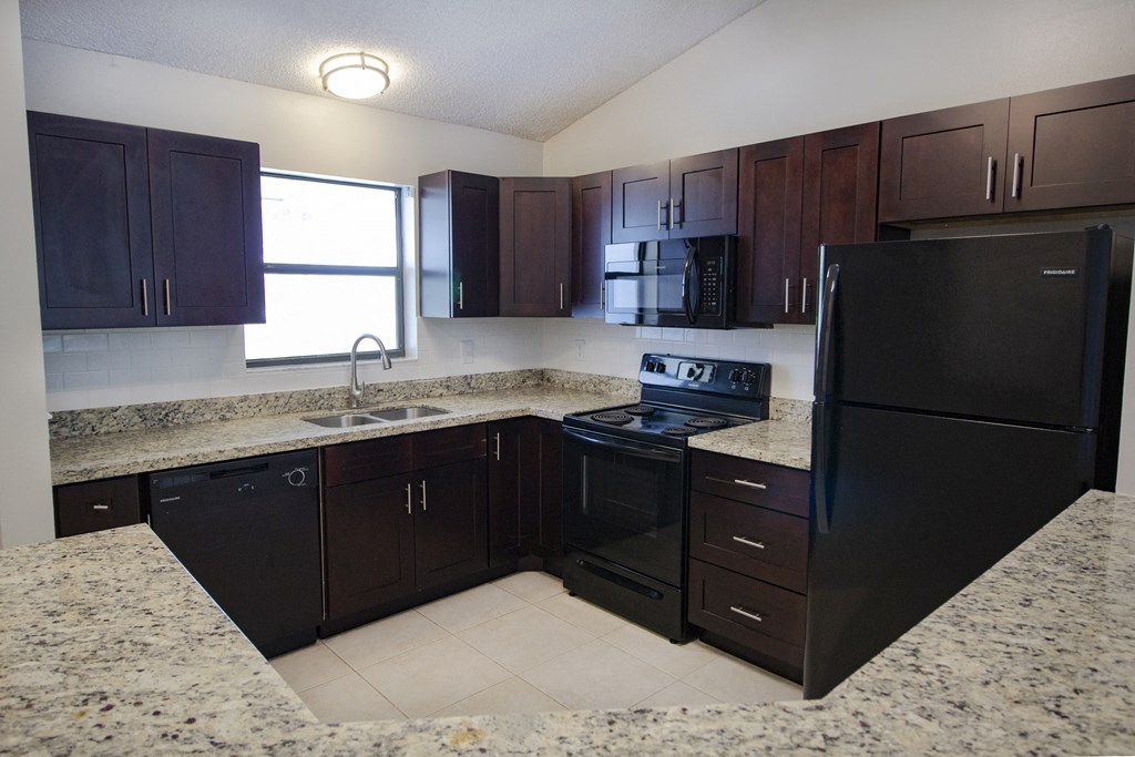 A kitchen with black cabinets and granite countertops.